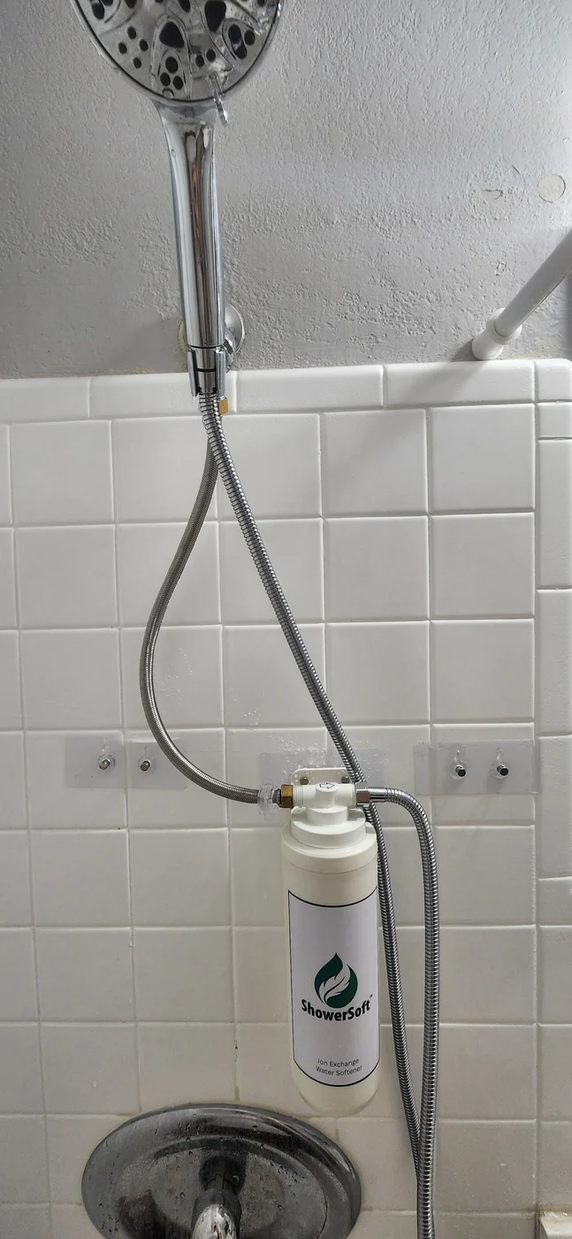 A ShowerSoft cartridge wall-mounted below a shower head with connected hoses